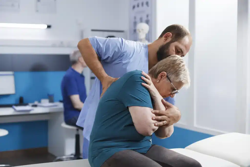 Chiropractor, assisting elderly patient