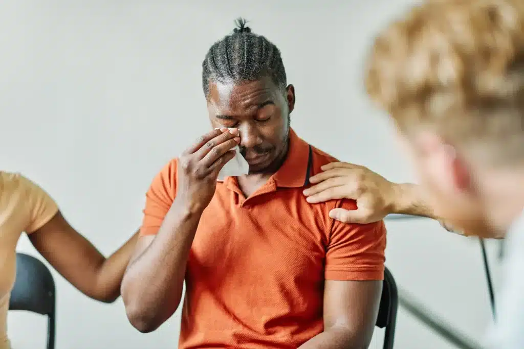Upset man being consoled by a group of people